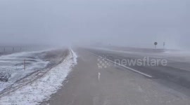 Wind and snow reduce visibility on Highway D20 in Iowa