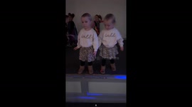 The video shows two-and-a-half-year-old twin girls at a party, playing together on a small stage area.Summer out of no where pushes Remi-Rae off the stage