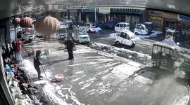 女子铲雪被雪块砸中 刚离开屋顶雪就如瀑布般滑落