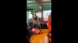Boat captain relaxes as he steers boat along choppy river