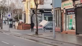 A man carrying a single mattress on his back walks down the street, reflecting the reality of life as an immigrant, London, England