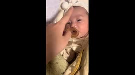 Mother gently swipes finger on baby's nose to send her to sleep in seconds