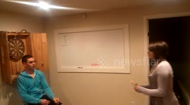 Drunk man lets woman throw dart while he sits below dart board, bad move