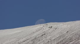 Remains of supermoon disappearing behind snow covered top of Morrone in Cairngorms Scotland