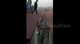 Students step across the gap between the roofs of two buildings