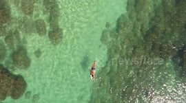 surfer paddling over a reef